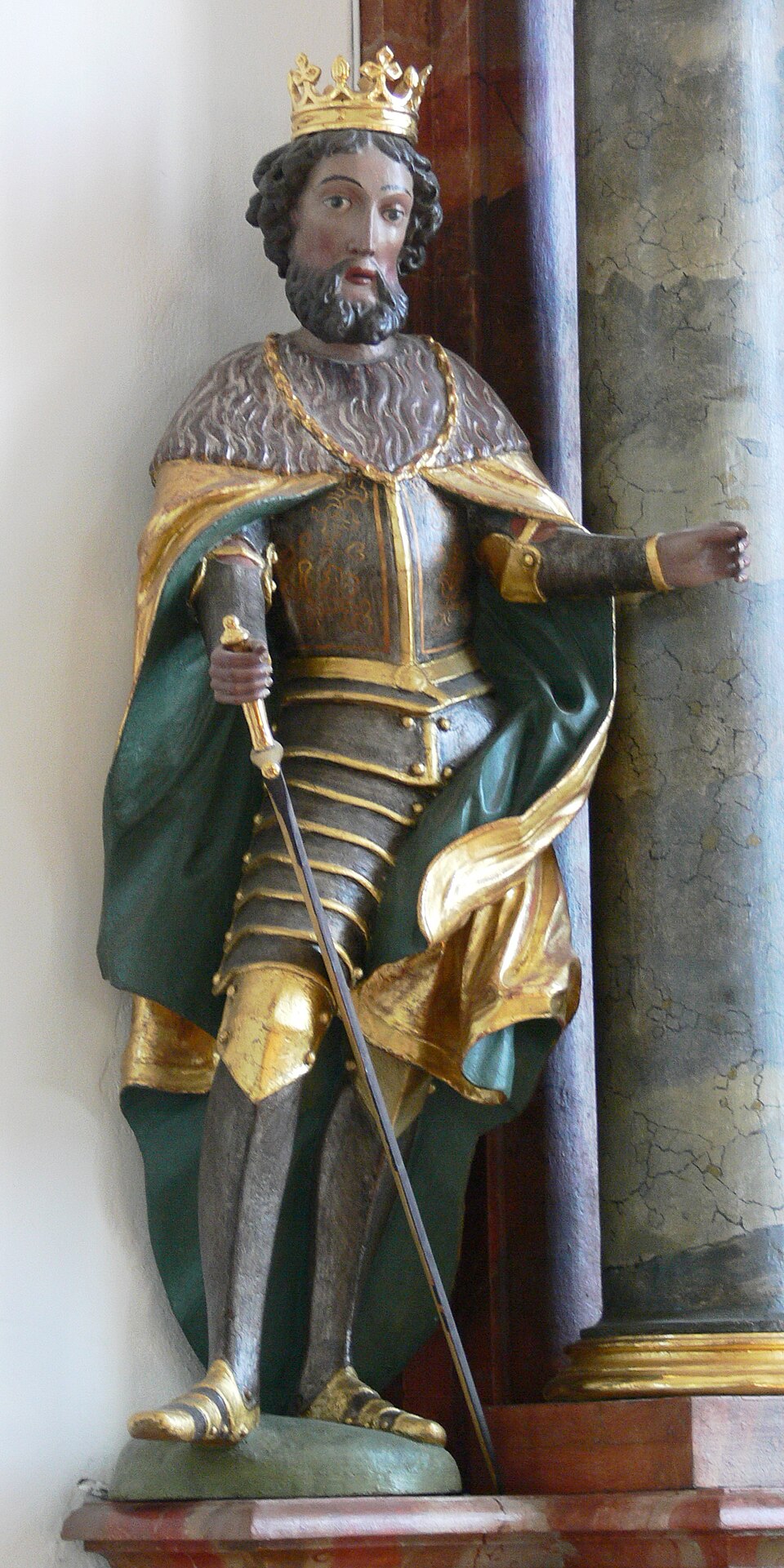 Escultura policromada de san Enrique con corona dorada, armadura, capa verde y espada en la mano