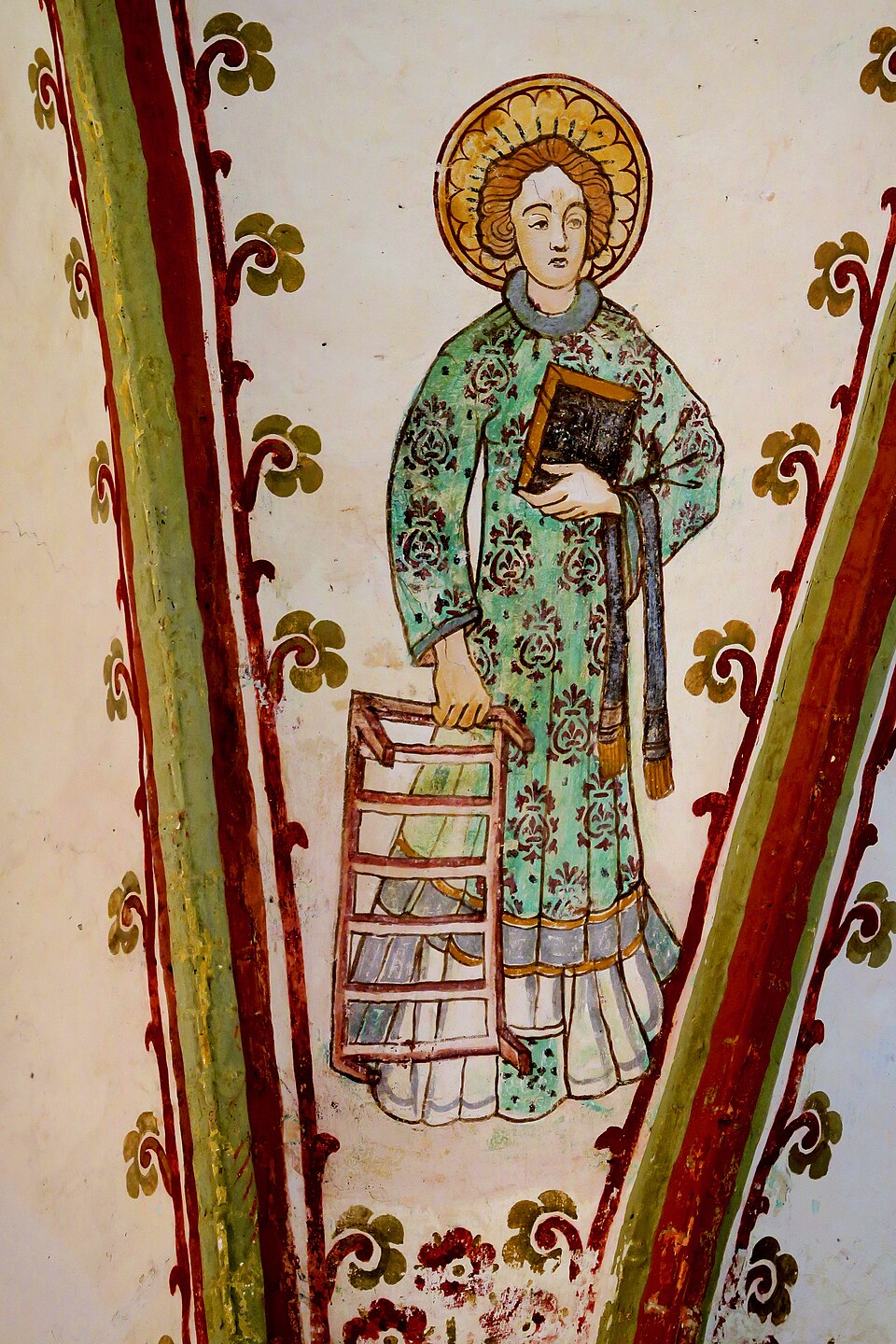 Pintura mural de san Lorenzo con dalmática verde y aureola, sosteniendo un libro y una parrilla