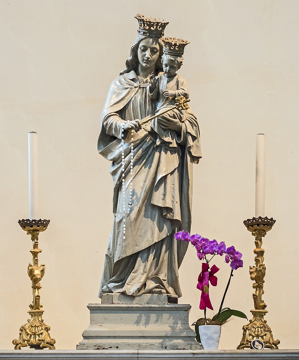 Imagen de María Auxiliadora coronada, con el Niño en brazos, cetro y rosario, entre dos candeleros dorados