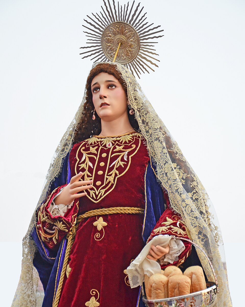 Imagen procesional de santa Marta con aureola de rayos, velo de encaje y una cesta con panes