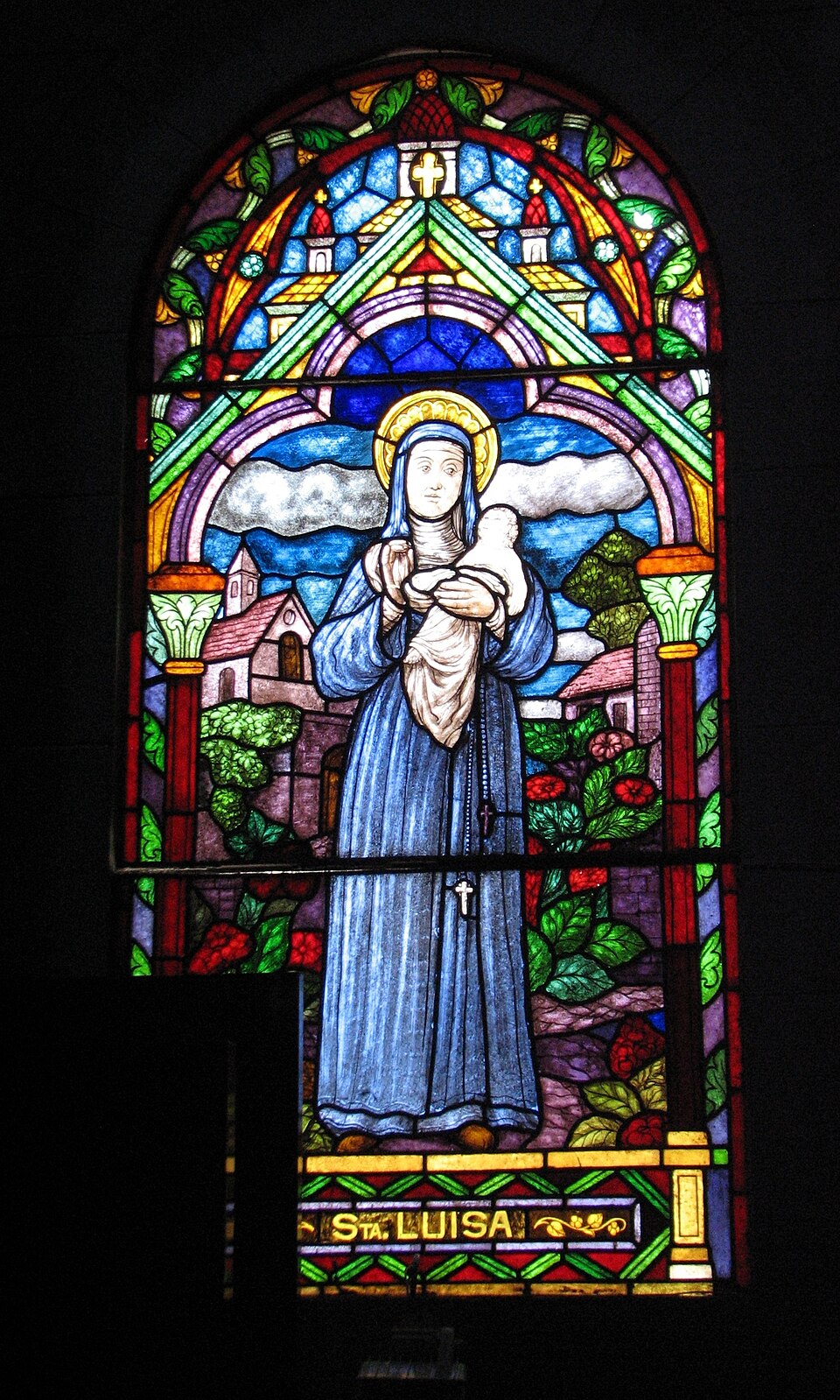 Vidriera de santa Luisa de Marillac con hábito azul, aureola y rosario, sosteniendo a un niño en brazos