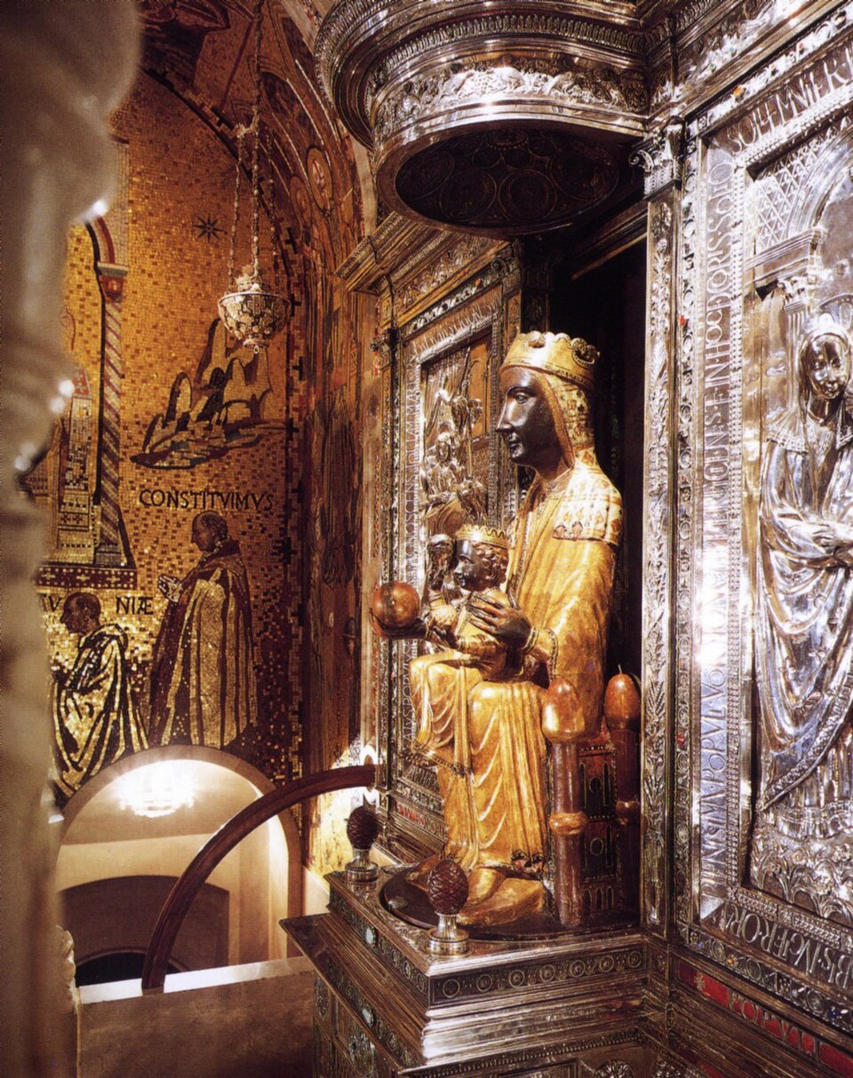 Talla dorada de la Virgen de Montserrat, de rostro oscuro y coronada, con el Niño en su camarín de plata