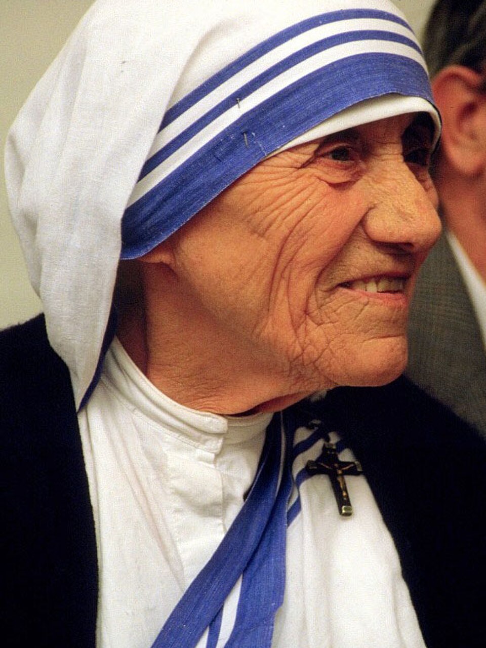 Fotografía de santa Teresa de Calcuta sonriendo, con su sari blanco de franjas azules y un crucifijo prendido