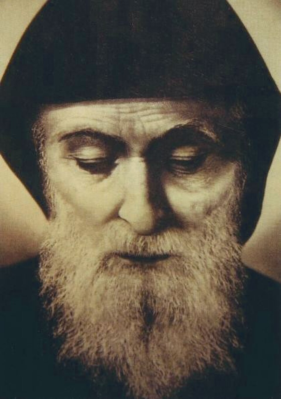 Imagen en sepia del rostro de san Charbel Makhluf, con barba canosa, capucha oscura y mirada baja