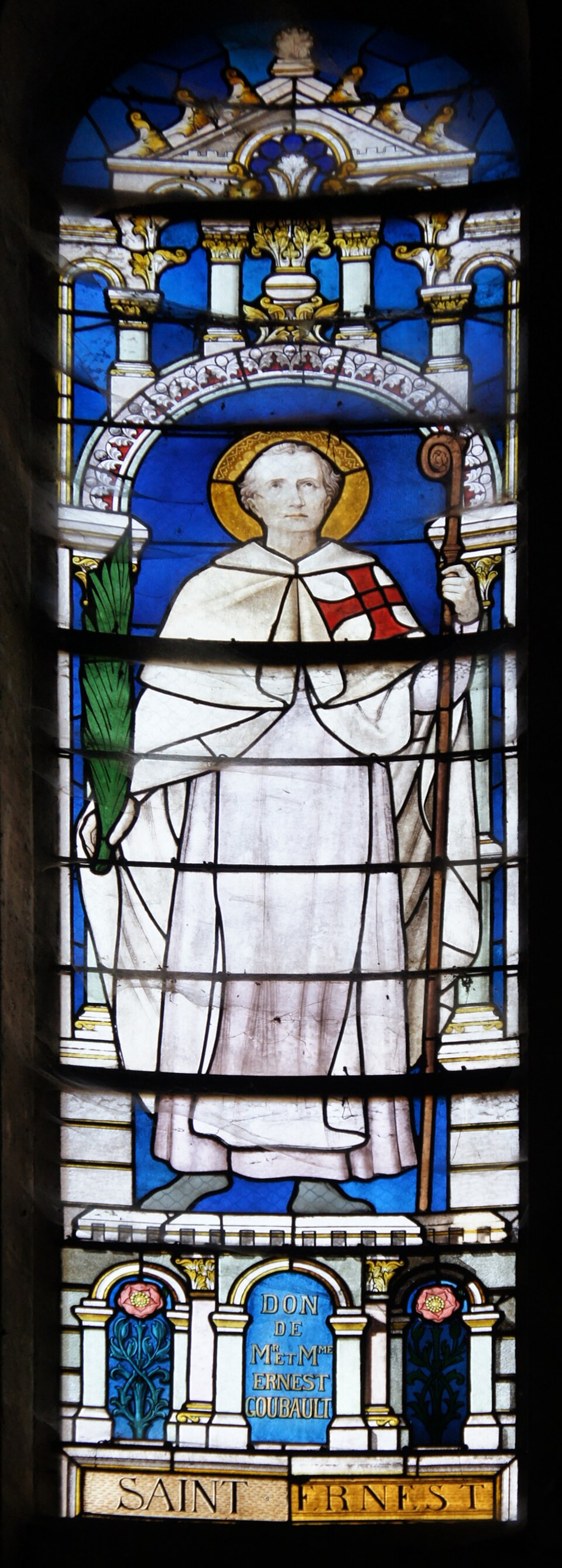 Vidriera de san Ernesto con aureola, capa blanca con cruz roja, palma en una mano y báculo en la otra