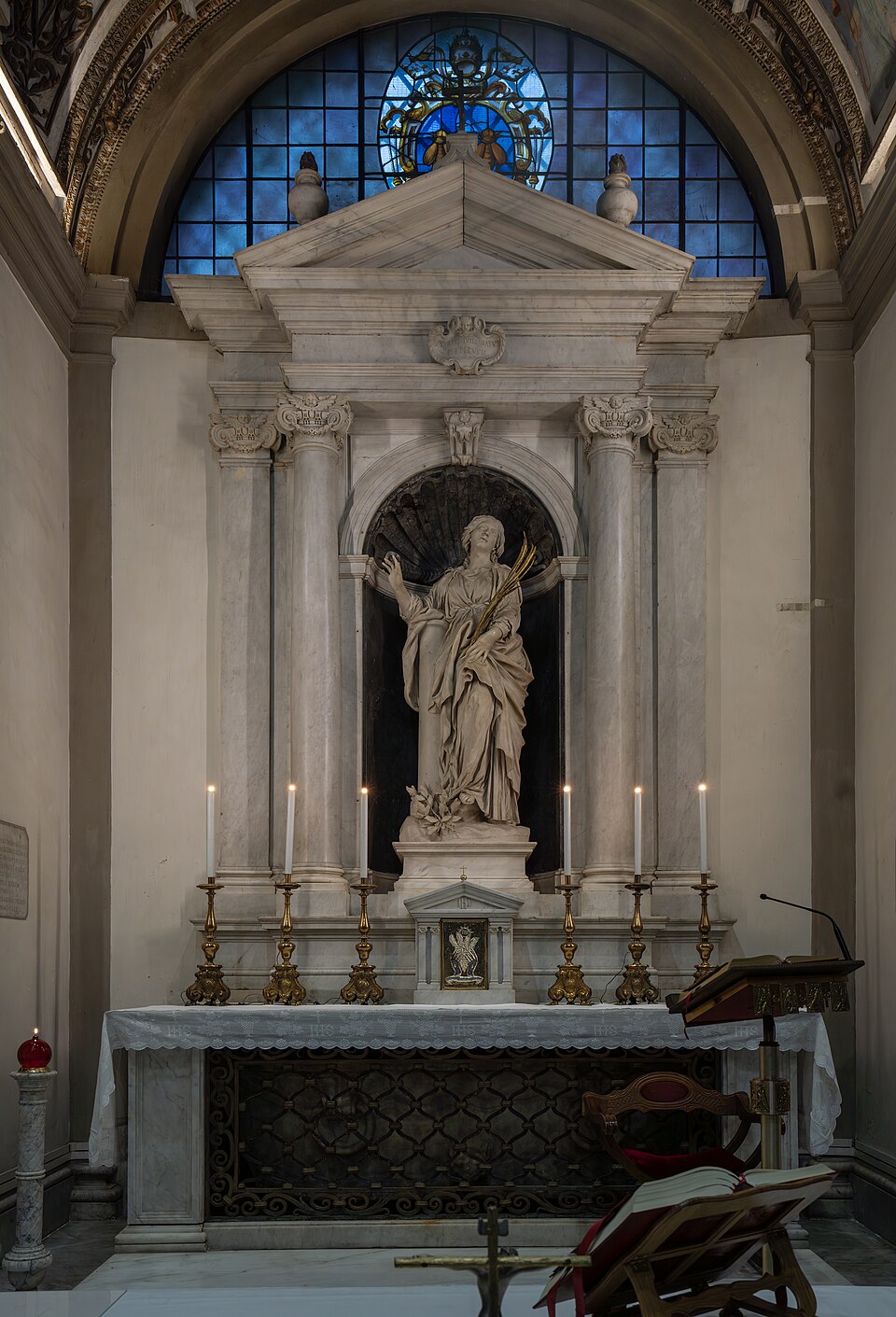 Altar con la estatua de mármol de santa Bibiana con palma, en una hornacina entre columnas y velas